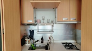 Eine kleine Küchenzeile mit eingebautem Kochfeld, Spüle und Stauraumschränken.