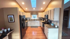 Una cocina moderna con piso de madera, armarios blancos y tragaluz.