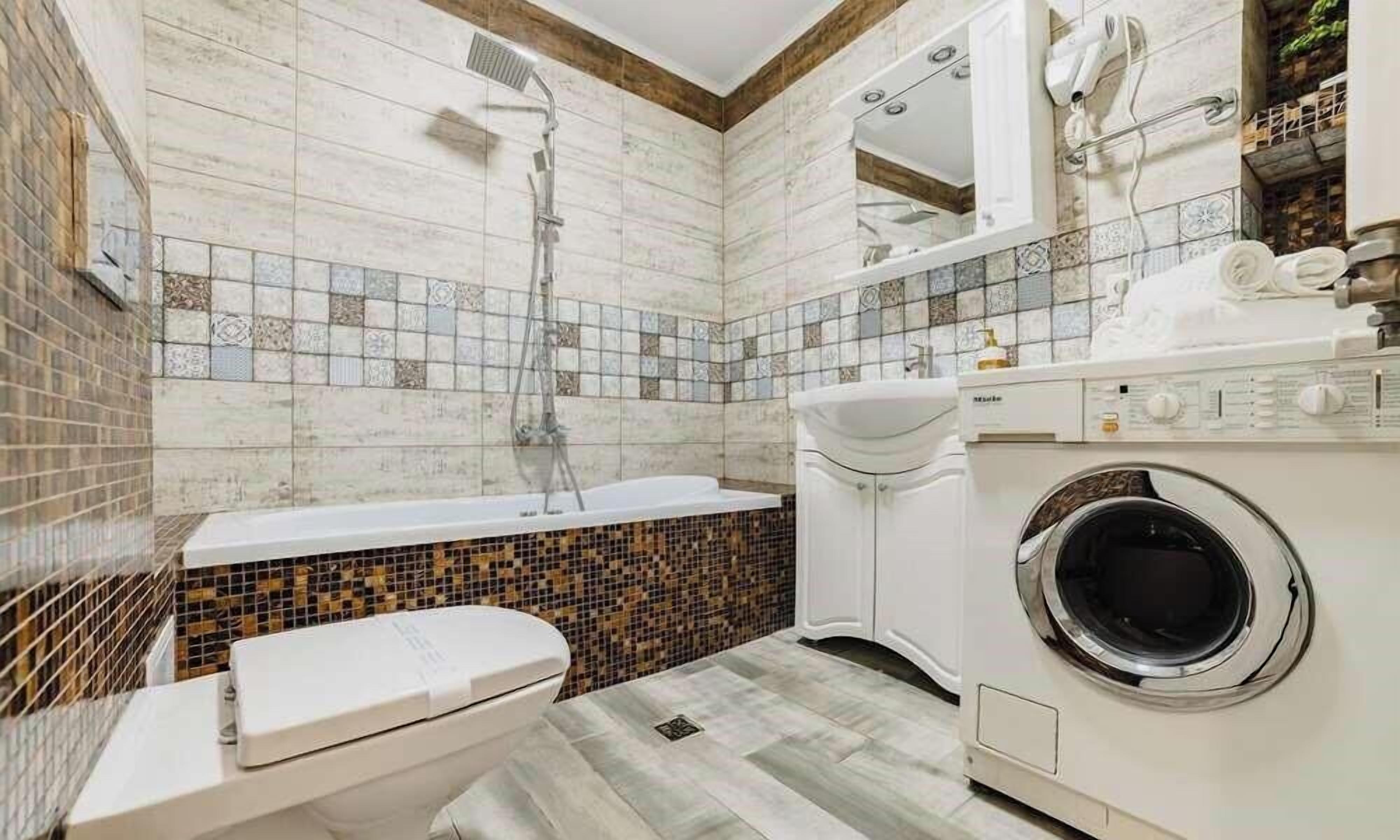 Un baño con bañera, inodoro y lavadora.