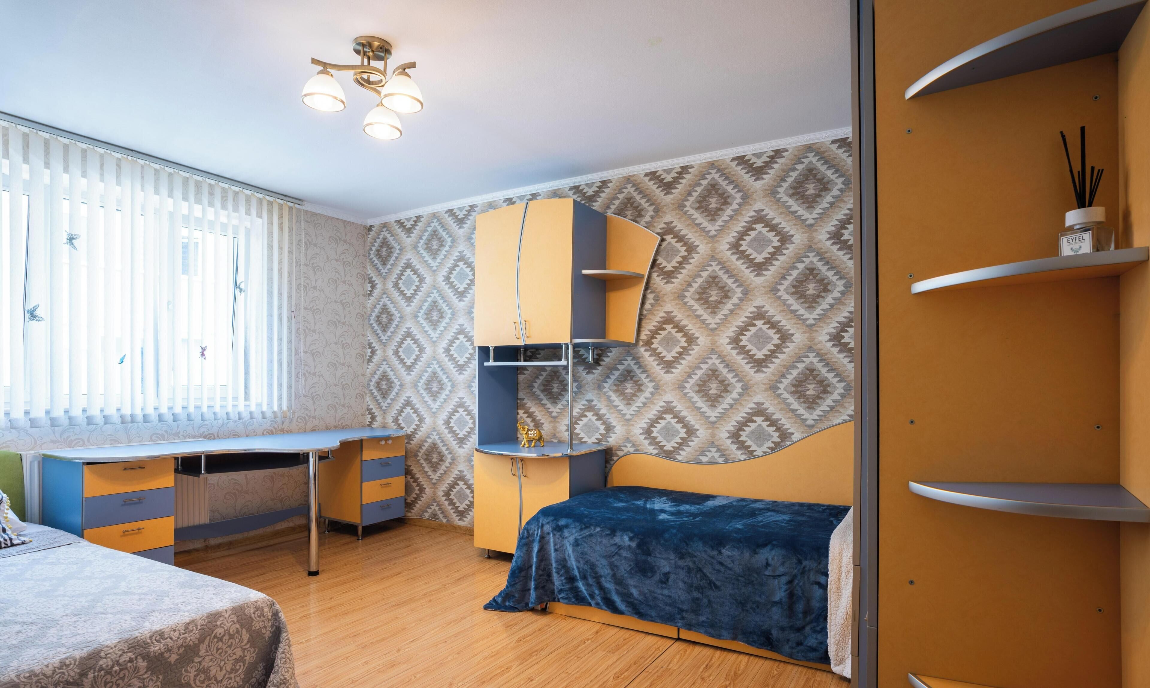 A compact bedroom with a bed, a desk, and a wardrobe.