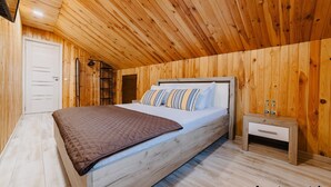 A wooden-paneled bedroom with a bed, bedside table, and a wardrobe. - Noua Oasis BNB with parking (Brașov)