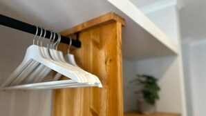 A wooden shelf with a white hanging rack holding several white hangers. - Villa Medusa Beach Studios, Seahorse (Parede)