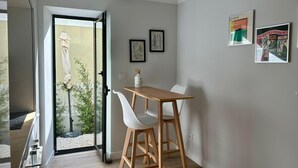 A modern dining area with a wooden table and white chairs, a glass door leading to an outdoor space, and framed artwork on the walls. - Villa Medusa Beach Studios, Seahorse (Parede)