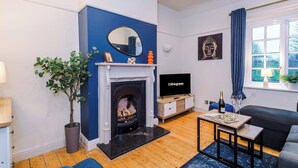 A modern living room with a fireplace, a television, and a comfortable seating area. - Charming City Centre 3 Bed Flat, High St Location! (Chester)