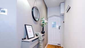 A hallway with a white door, a framed certificate, a mirror, and a small plant. - Charming City Centre 3 Bed Flat, High St Location! (Chester)