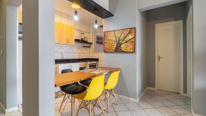 A modern kitchen with wooden cabinets, a dining table with yellow chairs, and pendant lighting. - Apartments 230m From the Beach in Ingleses - ZIO (Florianópolis)