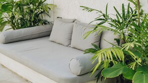 Un área de estar exterior moderna con pared blanca y techo de madera.