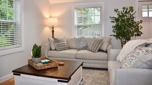 Ein Wohnzimmer mit einem beigen Sofa, einem Holztisch und einer Zimmerpflanze.