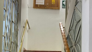 Un escalier avec une main courante, une porte fermée avec une pancarte et un panneau de sécurité.