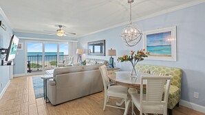 Un vaste espace de vie comprenant un balcon, une table à manger et un canapé.