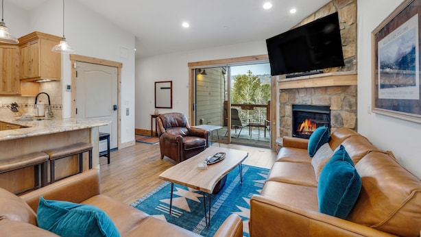 A spacious living area with a fireplace, leather sofa, and a television mounted on the wall.