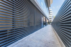 A narrow corridor with metal shutters on both sides, leading to a building entrance. - Official Mercury Suites | With Rooftop Pool Access (St. Julian`s)