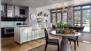 Una cocina moderna con una isla central, taburetes de bar y un comedor con una mesa redonda y sillas.