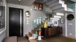 Un interior moderno con una escalera, un banco, un armario y un cuadro en la pared.