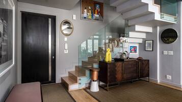 A modern interior with a staircase, a bench, a cabinet, and a wall-mounted picture.