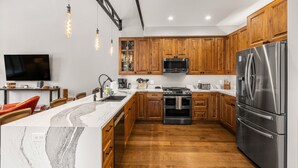 Una cocina moderna con armarios de madera, electrodomésticos de acero inoxidable y una isla de mármol.