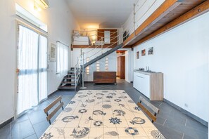A spacious hallway with a patterned floor, a staircase, a wooden bench, and a kitchen area.