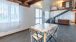 A dining area with a table, chairs, a staircase, and a view of the outdoors. - Apartment in Villa 'Il Limone, La Salvia e il Rosmarino' with Sea View, Private Terrace and Wi-Fi (Augusta)