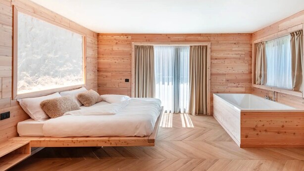 Une chambre à coucher moderne avec un lit, une grande fenêtre, une baignoire et des murs en bois.