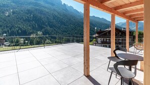 Une terrasse couverte avec vue sur les montagnes, une pergola en bois et deux chaises.