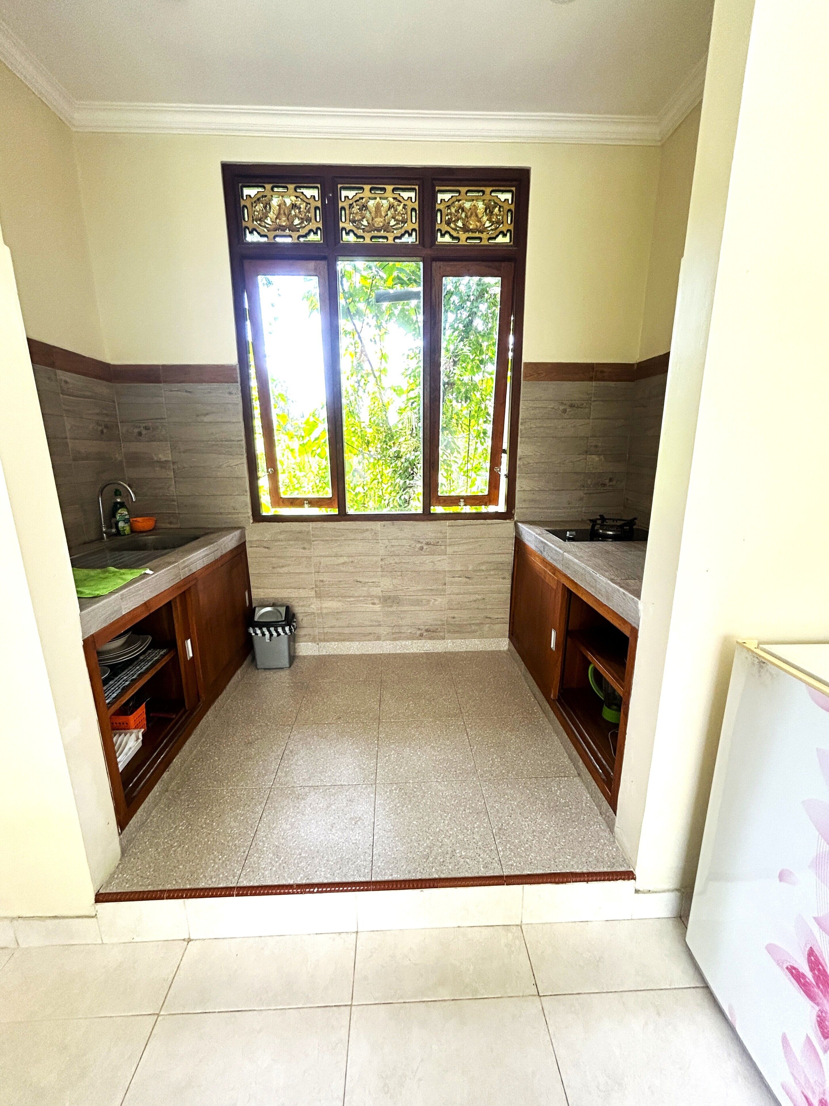 A kitchen with a window, wooden cabinets, and a tiled floor.