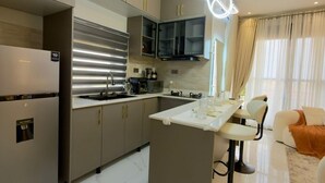 A modern kitchen with a central island, stainless steel appliances, and a dining area with bar stools. - Simba Heights Kyanja (Kampala)