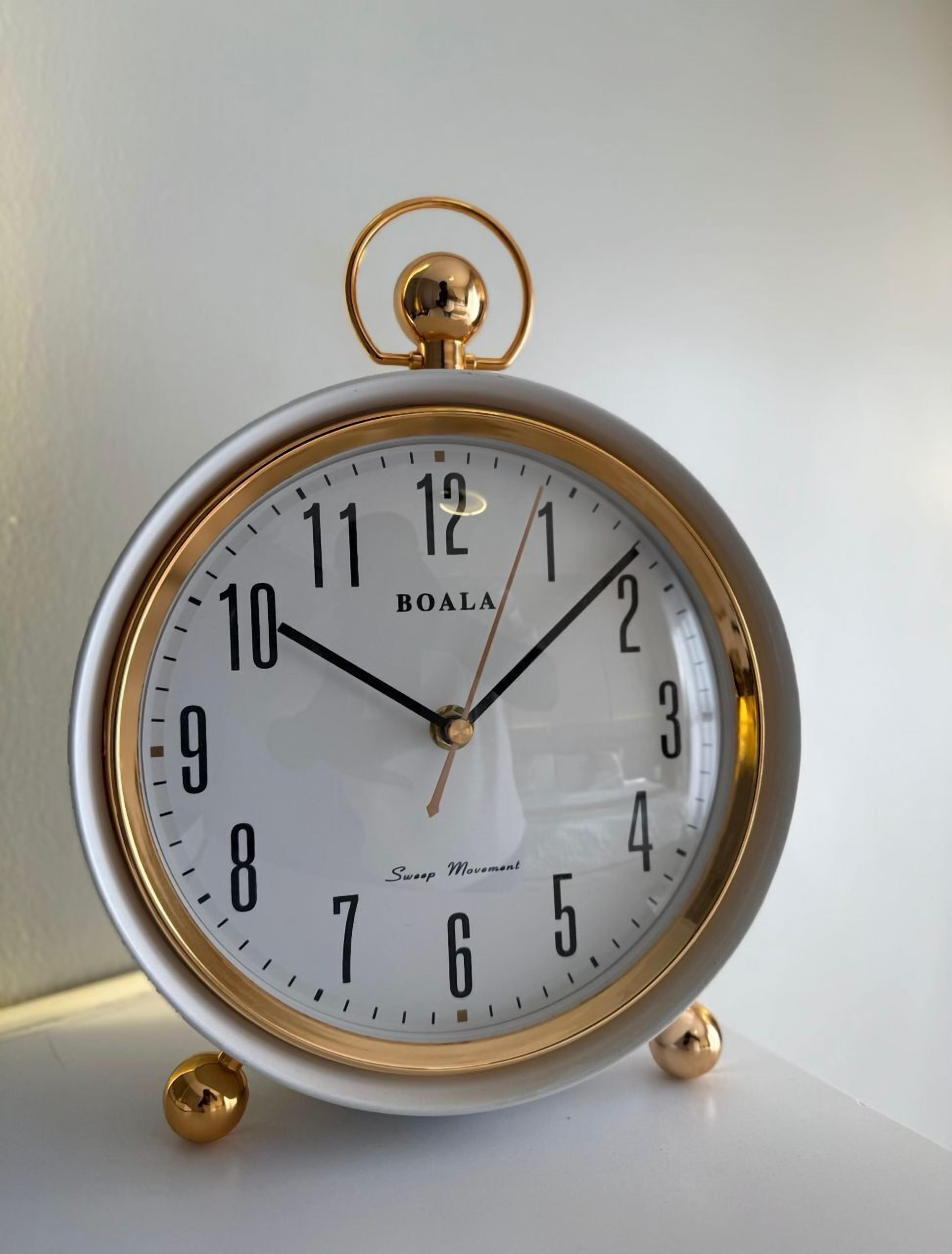 A BOALA wall clock with a white face and gold accents, featuring a sweep movement mechanism.
