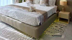 A modern bedroom with a large bed, a bedside table with a lamp, and a decorative tree sculpture. - Simba Heights Kyanja (Kampala)