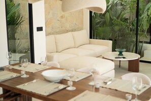 Ein moderner Essbereich mit einem Holztisch, der für eine Mahlzeit gedeckt ist, einer beigen Couch und einem runden Couchtisch.