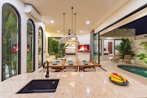 A modern kitchen with a marble countertop, a dining area with a pool view, and a living room with a fireplace. - 2BR Private Pool Villa Near Bingin Beach & Dreamland (Bali)
