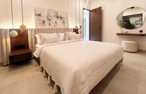 Ein modernes Schlafzimmer mit einem großen Bett, Nachttischen, einem Wandspiegel und einer Holztür.