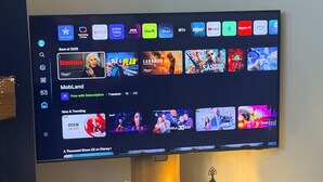 A flat-screen TV mounted on a wall displaying a streaming service interface with various content categories and thumbnails.
