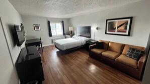 A hotel room with a bed, a sofa, a desk, and a TV. - Charming King Studio (Interior) (Lafayette)