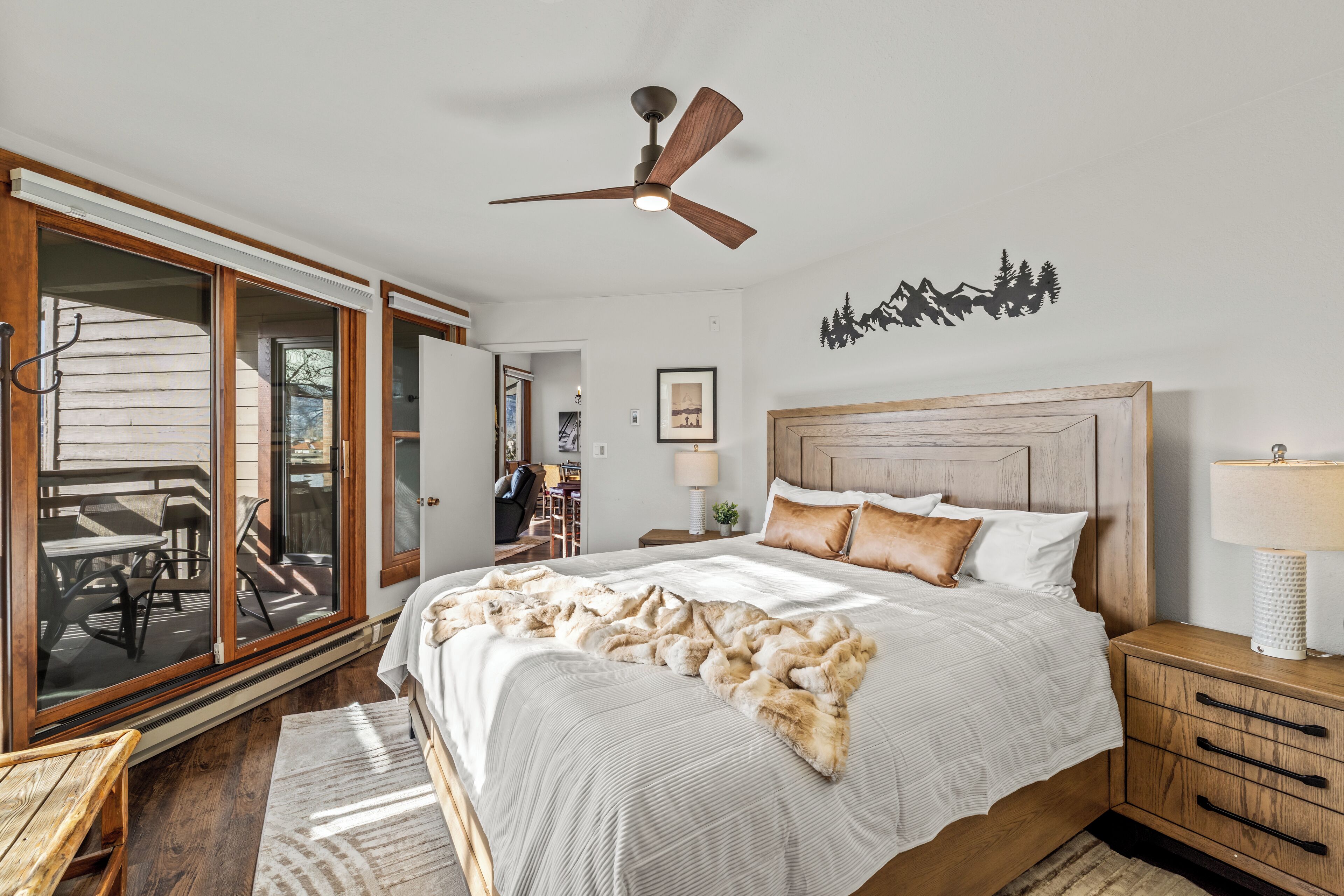 A bedroom with a large bed, wooden headboard, and a ceiling fan.