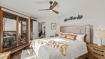 A bedroom with a large bed, wooden headboard, and a ceiling fan.