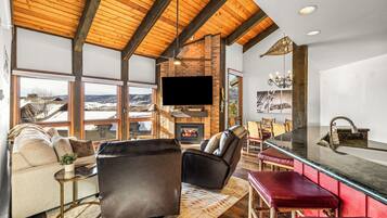 A spacious living room with a fireplace, leather seating, a large TV, and a view of the outdoors.