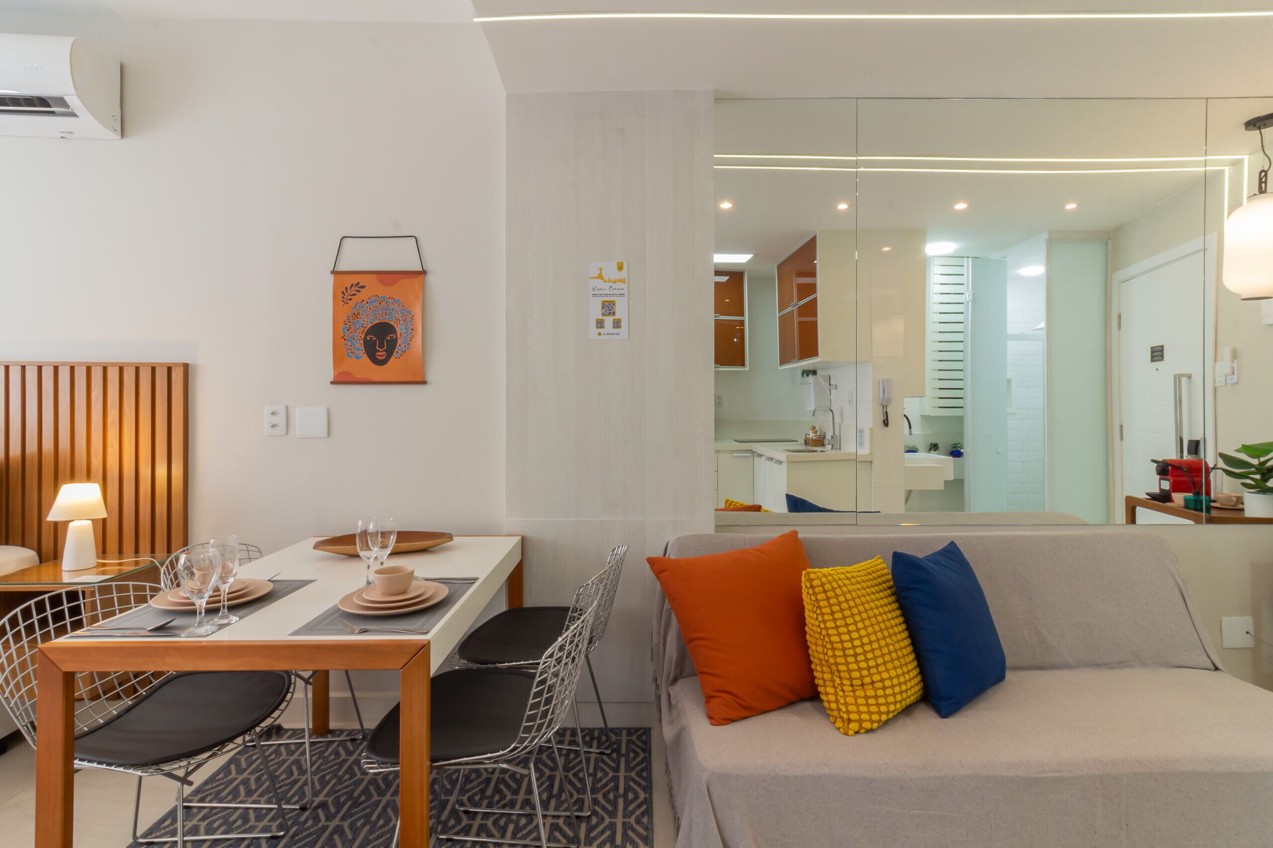 A modern living room with a sofa, a dining table with chairs, and a kitchen area in the background.