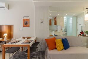 A modern living room with a sofa, a dining table with chairs, and a kitchen area in the background. - 5 Minutes From Copacabana Beach B703 (Rio de Janeiro)