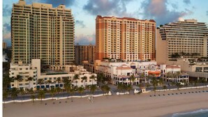 Ein Hotel direkt am Strand mit mehreren Hochhäusern, einem Sandstrand und Palmen.