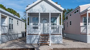A row of white mobile homes with a central structure featuring a porch and stairs.