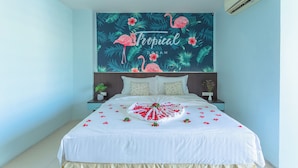Quarto com uma cama, parede com mural tropical, mesa de cabeceira com planta e aparelho de ar condicionado.