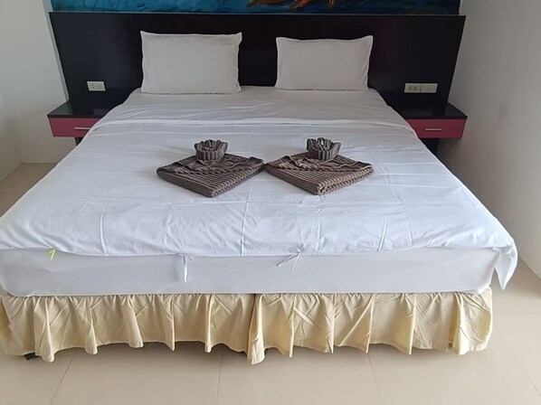 A neatly made bed with a white bedspread and two folded towels.