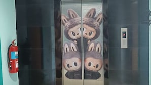Elevador com design de parede espelhada e personagem de desenho animado.