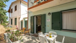 A two-story building with a balcony, outdoor seating area, and a table with chairs. - Relaxing Apartment Close to Santa Lucia Beach (Siniscola)