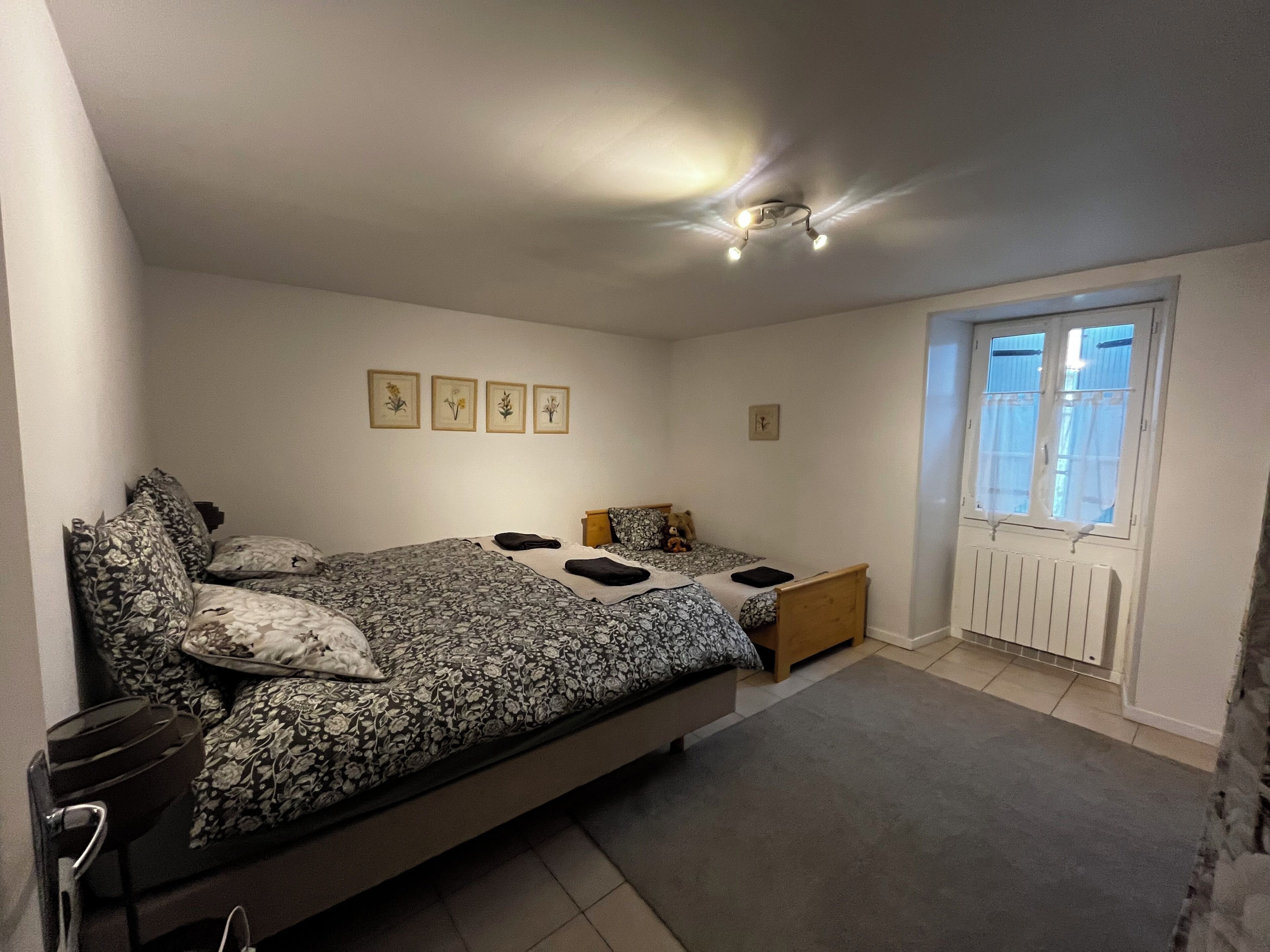 A bedroom with a bed, bedside tables, a window, and wall art.