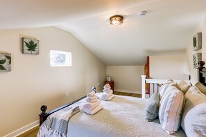Ein Schlafzimmer mit einem großen Bett, einem kleinen Fenster und einer Deckenleuchte.