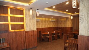 A restaurant interior with wooden paneling, recessed lighting, and multiple tables and chairs. - Hotel Nilax (Jaipur)
