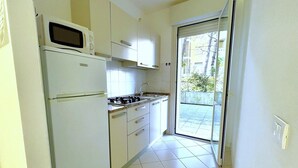 Cocina pequeña equipada con refrigerador, microondas, estufa y lavaplatos.