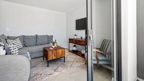 A modern living room with a grey sofa, a wooden coffee table, and a striped armchair. - Beach Break 17 (Cape Town)