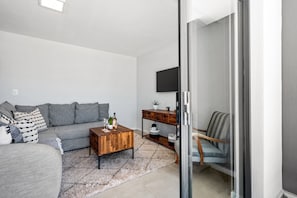 A living room with a sofa, coffee table, and a TV mounted on the wall. - Beach Break 17 (Cape Town)
